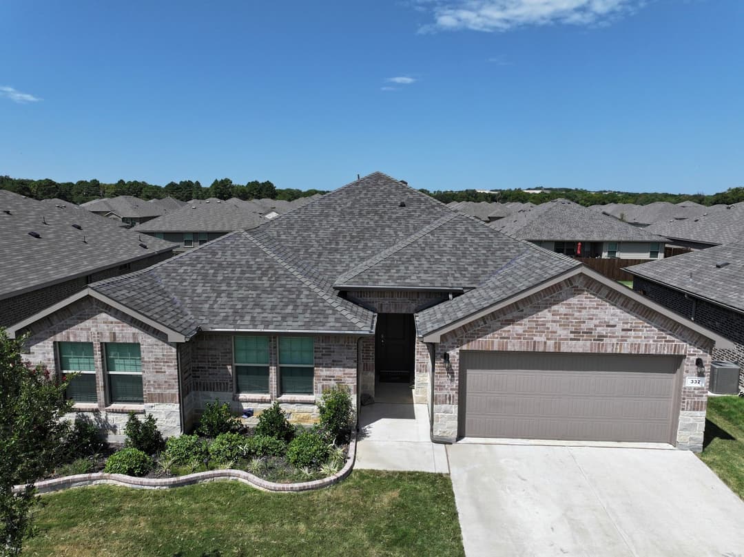 Single-story brick house with a landscaped front yard and garage on a sunny day.